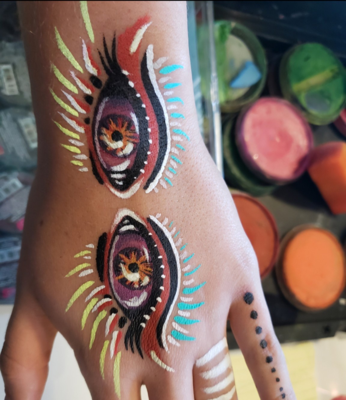 Colorful eye-inspired body painting on a hand